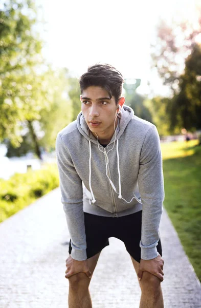 Runner in the city park resting, listening to music. — Stock Photo, Image