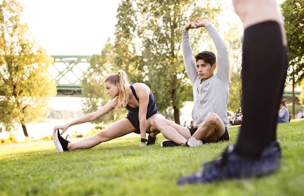 Jovens corredores se alongando e aquecendo no parque . — Fotografia de Stock