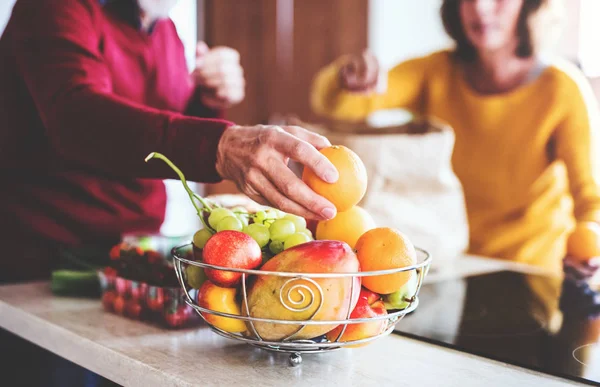 Seniorenpaar packt in der Küche Obst aus. — Stockfoto