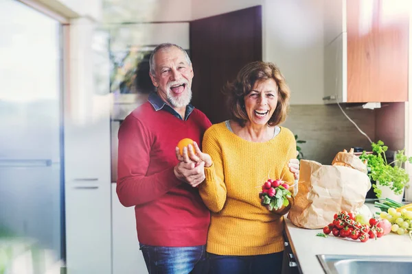 Coppia anziana disimballaggio cibo in cucina . — Foto Stock