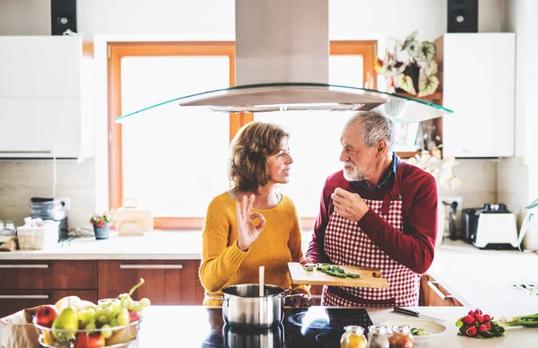 Casal sênior preparando comida na cozinha. — Fotografia de Stock