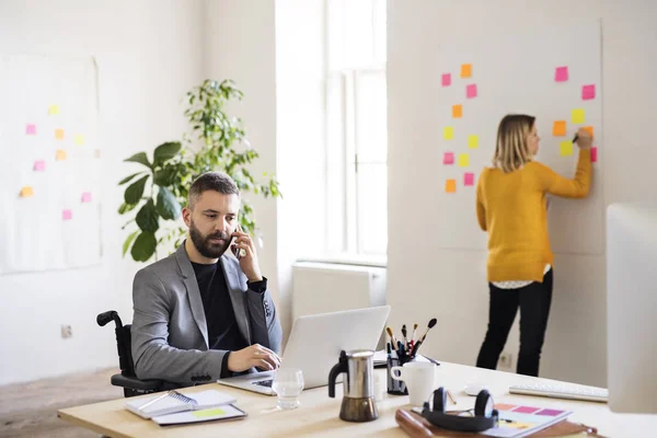 Two business people with wheelchair in the office. — Stock Photo, Image