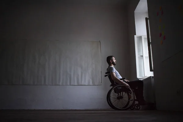 Человек в инвалидной коляске смотрит в окно . — стоковое фото