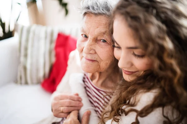 En tonårig flicka med mormor hemma, kramas. — Stockfoto