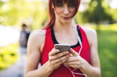 Müzik genç atlet akıllı telefon, holding Park.