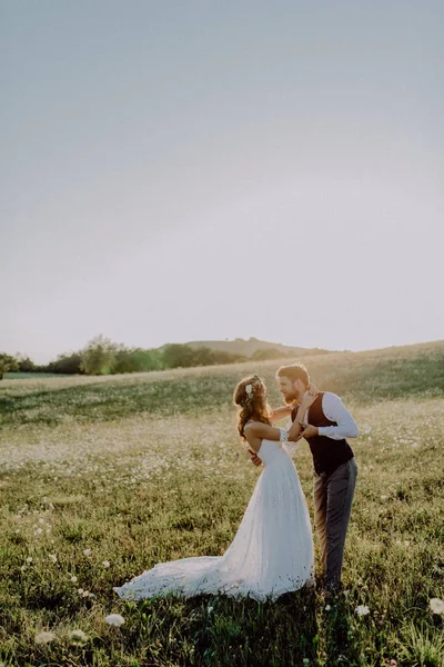 Mooie bruid en bruidegom bij zonsondergang in de groene natuur. — Stockfoto