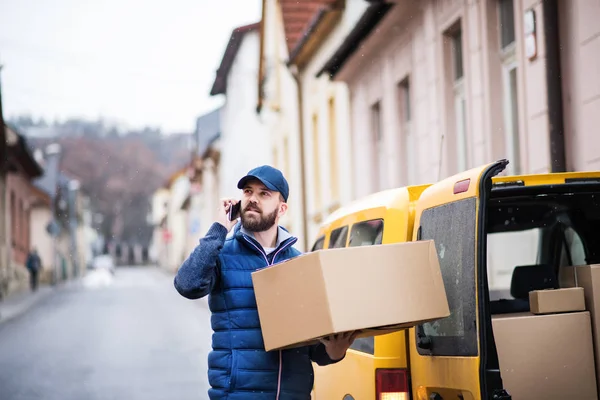 Szállítási ember az utcán egy csomag doboz. — Stock Fotó