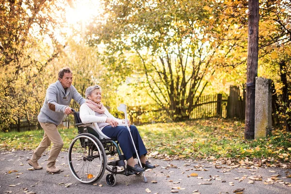 Starszy mężczyzna i kobieta na wózku inwalidzkim w jesień natura. — Zdjęcie stockowe