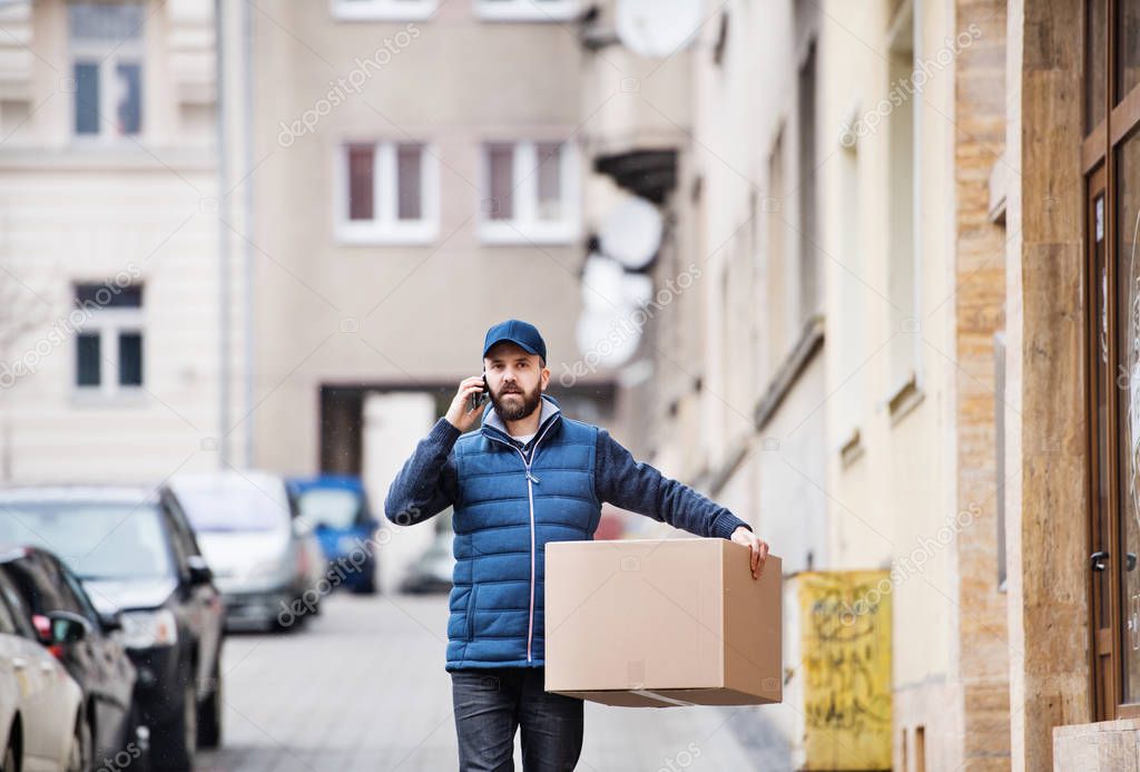 Delivery man with a parcel box on the street.