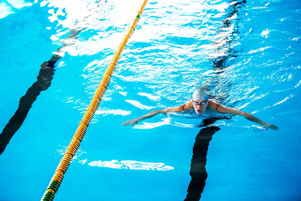 Старший мужчина плавает в закрытом бассейне
.