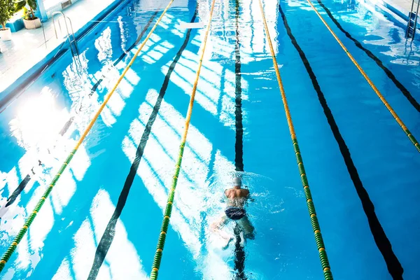 Senior homem nadando em uma piscina interior . — Fotografia de Stock