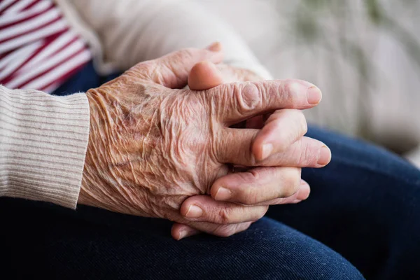 Biddende handen van een senior vrouw thuis. — Stockfoto