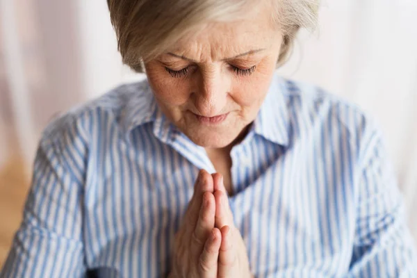 Eine ältere Frau betet zu Hause. — Stockfoto