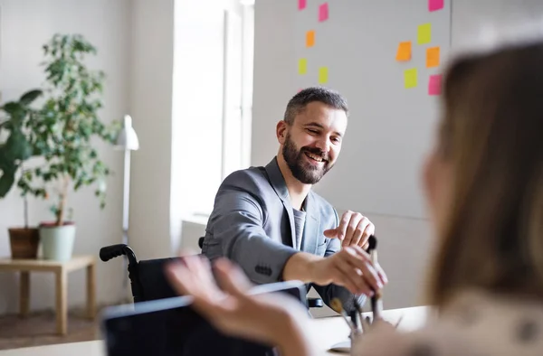 Zwei Geschäftsleute mit Rollstuhl im Büro. — Stockfoto