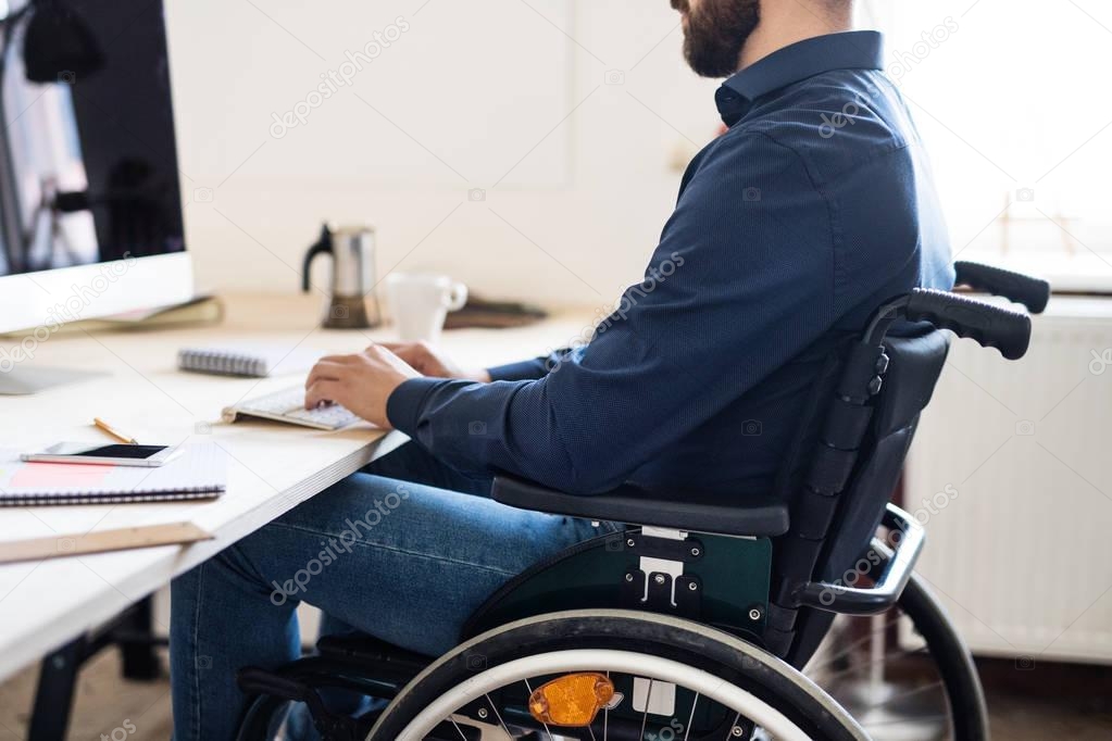 Businessman in wheelchair working in his office.