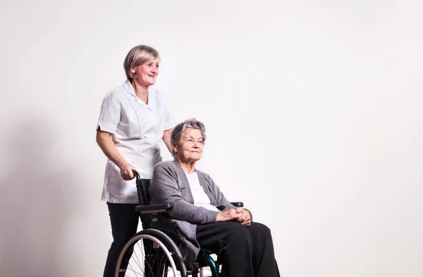 휠체어와 간호사 고위 여자의 스튜디오 초상화. — 스톡 사진