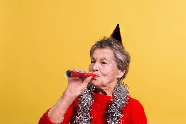 Portrait of a senior woman in studio on a yellow background. Party concept. — Stock Photo, Image