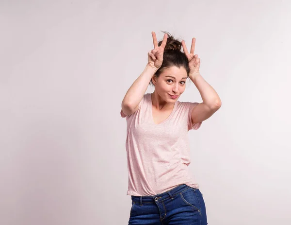 Joven hermosa mujer en estudio haciendo orejas de conejo . — Foto de Stock