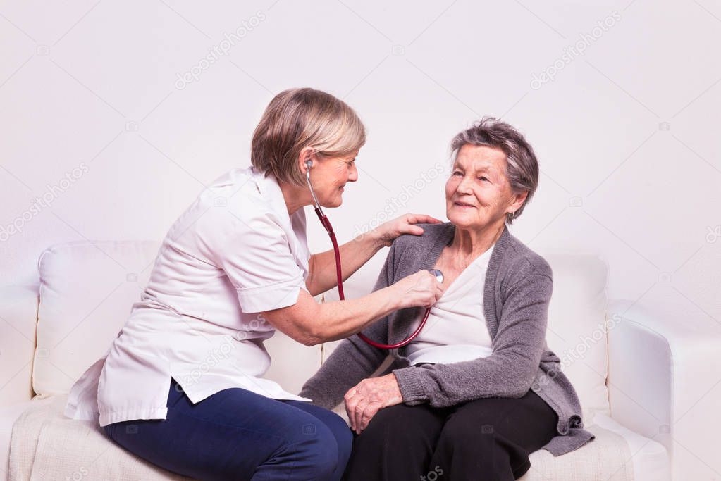 Studio portrait of a senior nurse examining an elderly woman.