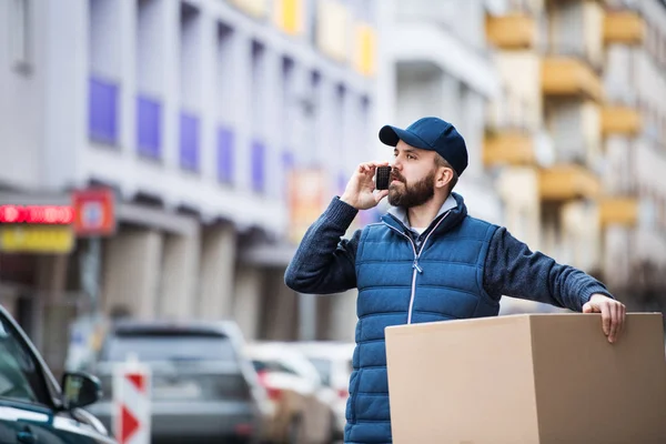 Delivery man with a parcel box on the street. — Stock Photo, Image