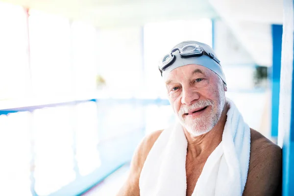 Senior man die door een overdekt zwembad. — Stockfoto