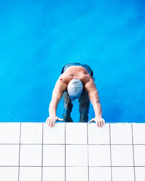 Senior man in een overdekt zwembad. — Stockfoto