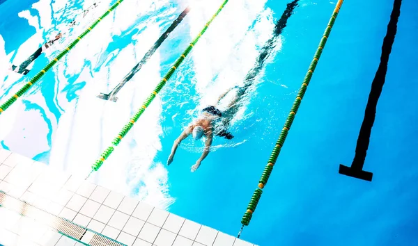 Hombre mayor nadando en una piscina cubierta . — Foto de Stock