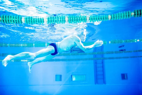 Homme âgé nageant dans une piscine intérieure . — Photo