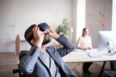 Tekerlekli sandalye ve Vr iki iş adamları gözlükler ofiste.