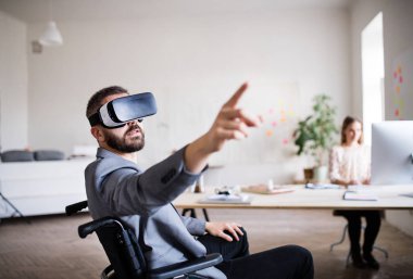 Tekerlekli sandalye ve Vr iki iş adamları gözlükler ofiste.