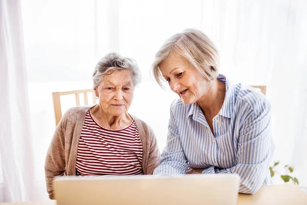 Mulher sênior com sua mãe com laptop em casa . — Fotografia de Stock