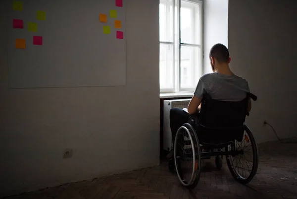 Adam tekerlekli sandalyeye mahkum pencereden dışarı bakıyor. — Stok fotoğraf