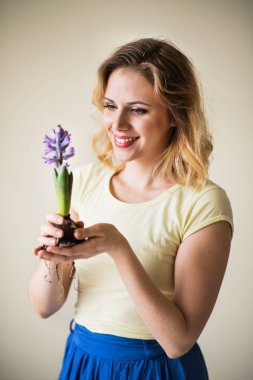 Evde çiçek fide tutan genç kadın.