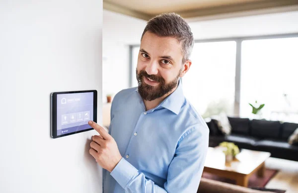 Ein Mann zeigt auf ein Tablet mit Smart-Home-Bildschirm. — Stockfoto