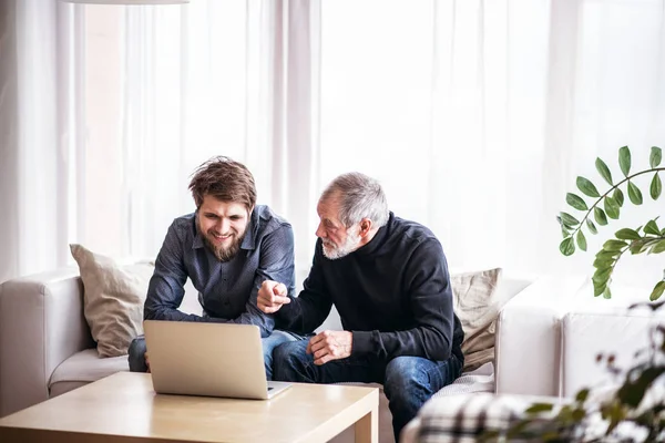 Hipster fils et son père aîné avec ordinateur portable à la maison . — Photo