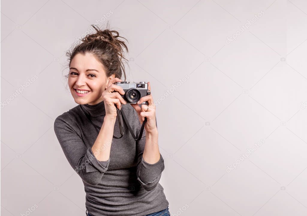 Portrait of a young beautiful woman with camera in studio.