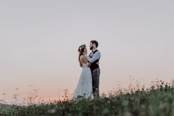 Bela noiva e noivo ao pôr do sol na natureza verde . — Fotografia de Stock