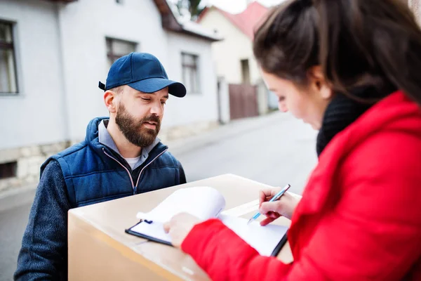 Mujer recibiendo el paquete del repartidor en la puerta . — Foto de Stock