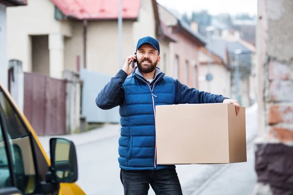 Repartidor con una caja de paquetes en la calle . — Foto de Stock