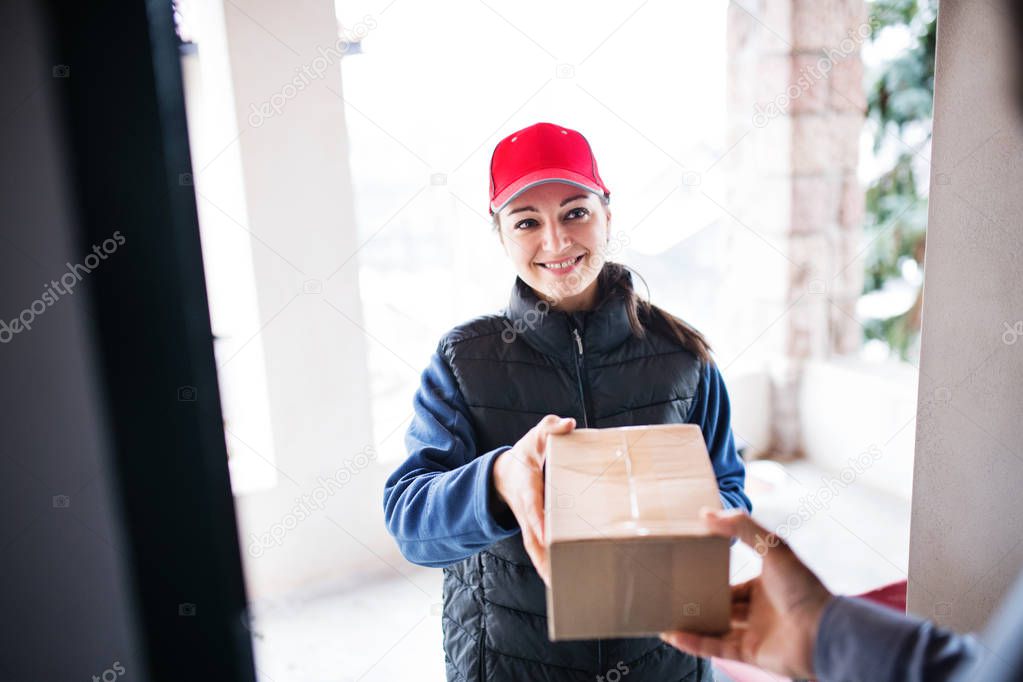 A man receiving parcel from delivery woman at the door.