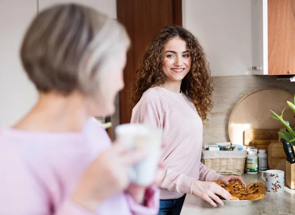 A teenage girl with mother in the kitchen at home. — Stock Photo, Image