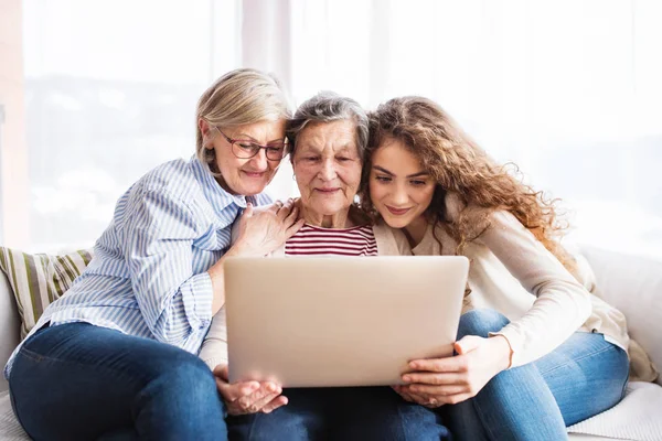 Seorang gadis remaja, ibu dan nenek dengan laptop di rumah . — Stok Foto