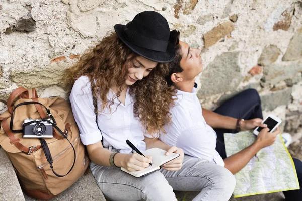 Dos jóvenes turistas con un smartphone en el casco antiguo . — Foto de Stock