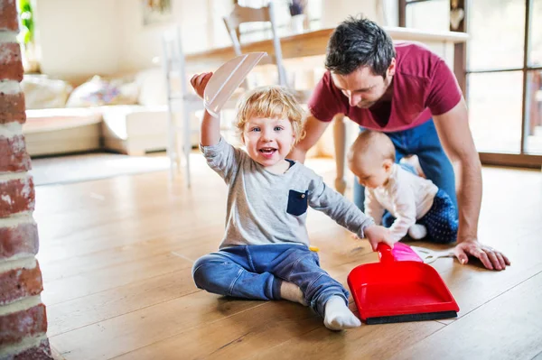 Vater und zwei Kleinkinder mit Pinsel und Kehrschaufel. — Stockfoto