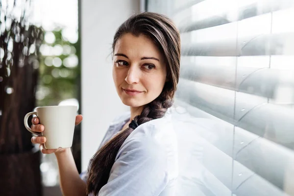 Donna dalla finestra che tiene la tazza di caffè . — Foto Stock