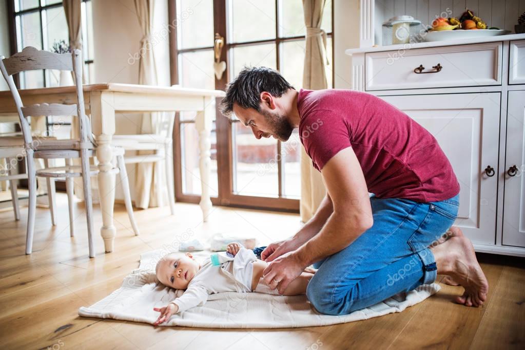 Father changing a baby girl at home.