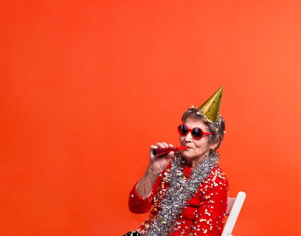 Portrait of a senior woman in studio on a red background. Party concept. — Stock Photo, Image