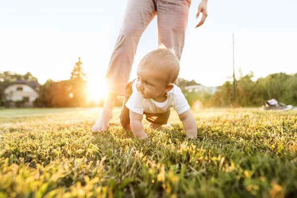 Baby boy with unrecognizable mother crawling outside. — Stock Photo, Image