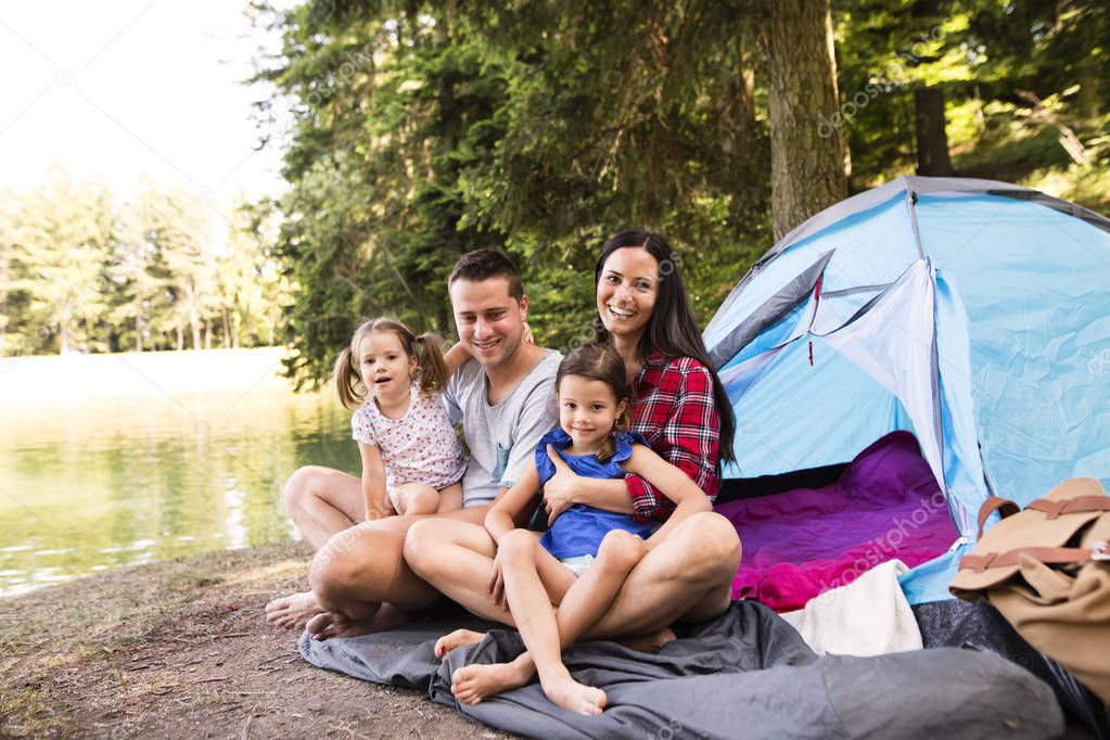 Beautiful young family with daughters camping in forest.