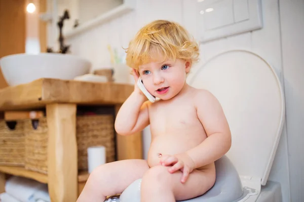 Menino bonito da criança com smartphone no banheiro . — Fotografia de Stock